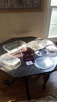 Clear Pyrex glass baking pans (two 11x7x1.5 and one 13x9x2) and assorted lids displayed on a wooden table under window light.