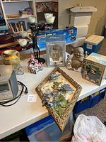 Wide angle of assorted decorative items including fountain, frame, Buddha statue, house figurine, and electronics on table.
