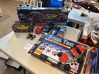 Wide view of all items on table, featuring boxed construction set, remote control car, helicopter, and multiple toy cars.