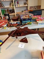 Overview photo showing the wooden helicopter on a stand with board games in the background.