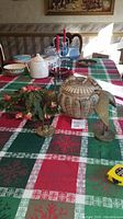 Photo showing pottery bowl with carved design and brass bird sculptures on a festive tablecloth.