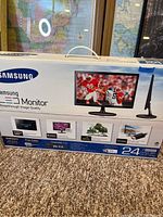 Photo of Samsung 24-inch LED Monitor box showing front and side details including features and model info.