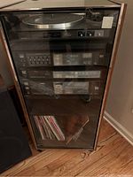 Full view of the Sanyo stereo system and entertainment center with glass front showing electronics and albums below