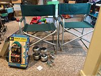 Two green stadium chairs, two battery-operated lanterns, boxed Space Logic 2-pocket organizer, and a child's chair seen in a basement setting