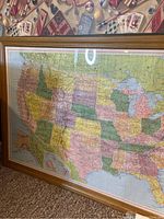 Framed multi-color United States map showing detailed state borders with wood-toned frame and glass cover.