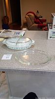Full view of the Pyrex baking dish with both glass lids on a countertop with a chair and boxes in background