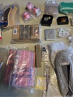 Overview of most lot contents showing shoe cushions, makeup sponges, boxed Avon products, and small accessories on table