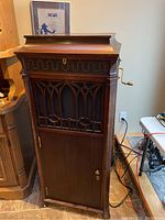 Full front view of dark stained oak cabinet with decorative grille and locked lower door