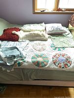 View of Dresden quilt with circular floral patchwork, various handmade crochet pillows, and afghan blankets arranged on bed.