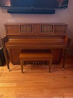 Front view of Kawai 801C upright piano with bench in place on a hardwood floor, showing full piano and bench structure.