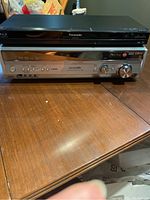 Front view of Panasonic receiver and Blu-ray player stacked together on a wooden table.
