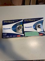 Photo of two Panasonic BL-C30C wireless remote video monitoring cameras in original packaging on a white surface, one box partially obscured by a green label.