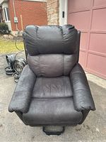 Front view of black remote controlled lift chair showing cushioned seat and backrest with slight wear.