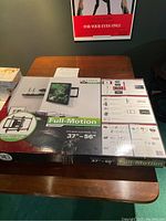 Sealed box of Sanus Full Motion Motorized Wall Mount for 37 to 56 inch TVs showing front and side packaging with model number and features.