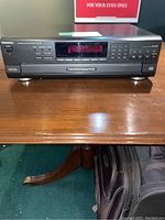 Front view of the Technics 5 disc CD changer on wood surface, showing digital display and control panel.