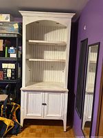 Full front view of vintage white cabinet showing two shelves and two-door base storage.