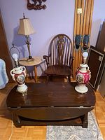 Photo showing entire lot furniture and lamps in corner of room with purple walls, including drop leaf table, occasional table, spindle chair, lions foot lamp, and two Victorian scene lamps.