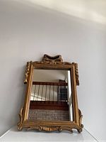 Front view of antique mirror showing full frame with top ribbon motif.
