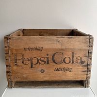 Front view of the wooden Pepsi-Cola crate showing the printed logo and text on one side.