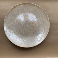 Top view of the iridescent decorative bowl showing detailed peacock feather pattern and finish wear.