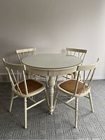 Full view of round table with glass top and four matching chairs