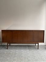 Front view of closed teak credenza showing two bi-fold doors and splayed legs