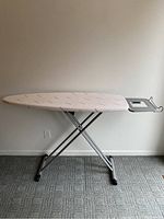 Full side view of Rowenta ironing board showing beige cover, metal frame, and overall shape.
