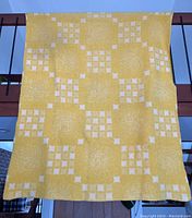 Blanket hanging showing yellow side with geometric square pattern.