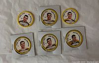 Photo of 6 circular hockey coins featuring Boston Bruins players from 1961-1967 with photographs, names, and dates.