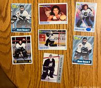 Top view of 7 Manon Rheaume hockey cards arranged on a wood table showing front of each card featuring goalie poses and portraits.