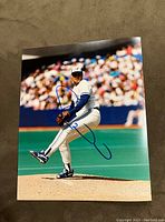 Front of autographed Duane Ward 8x10 photo showing him pitching on the field.