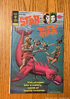 Front cover of Star Trek comic #43 showing Captain Kirk on a pink sea monster fighting hostile mutants underwater.