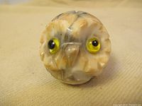 Front view showing carved owl face with yellow glass eyes and carved feather details.