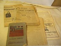 Four antique newspapers with yellowed pages, stacked loosely, showing visible wear and an additional booklet titled 'Little Journeys' by Elbert Hubbard.