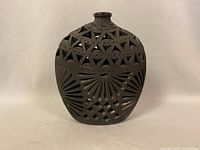 Front view of argillite vase showing carved triangular and fan-shaped patterns with cutouts.