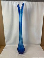 Full view of tall blue blown glass vase showing elongated neck and flared pointed top.
