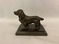 Solid copper dog paperweight shown from side profile on off-white background.