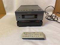 Two stacked Sony compact disc receiver units with a power cord and remote control placed in front.