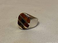 Angle view of the ring showing the side profile and thickness of the band with multi-stone inlay detail.
