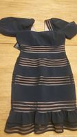 Front view of black BCBG dress showing sheer horizontal stripes and flounced hem with stripes