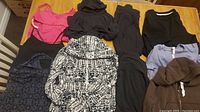 Lot spread showing multiple Lululemon clothing items including hoodies, tank tops, pants, and shirts in black, pink, brown, and patterned fabrics.