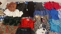 Overview of mixed vintage 1970s-1980s women's clothing laid out flat on fabric background including skirts, blazers, pants, and shorts in various colors and patterns.