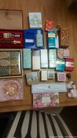 Top view showing entire lot arranged on wooden surface with various boxed fragrances and soaps in different sizes and shapes, some with original packaging visible.