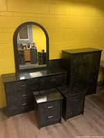 Bedroom furniture set with armoire, dresser with vanity mirror, two end tables, and headboard all in black marbled finish.