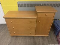 Photo of wooden baby change table with drawers and closed cabinet door, showing overall form and condition