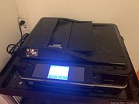 Epson Artisan 835 printer powered on with touchscreen display lit, positioned on cart.