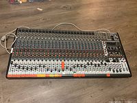 Top view of entire mixer showing control surface with faders, knobs, XLR and TRS inputs and attached power cable.