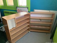 Two woodgrain finish shelving units, one with white plastic paper sorter rack on left side, both on caster wheels.