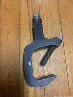 Single metal spotlight clamp shown on a wooden floor, illustrating the shape and tightening bolt.