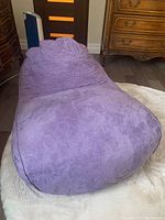 Front view of the purple children's floppy chair with cushioned and fabric-covered surface showing subtle pattern.